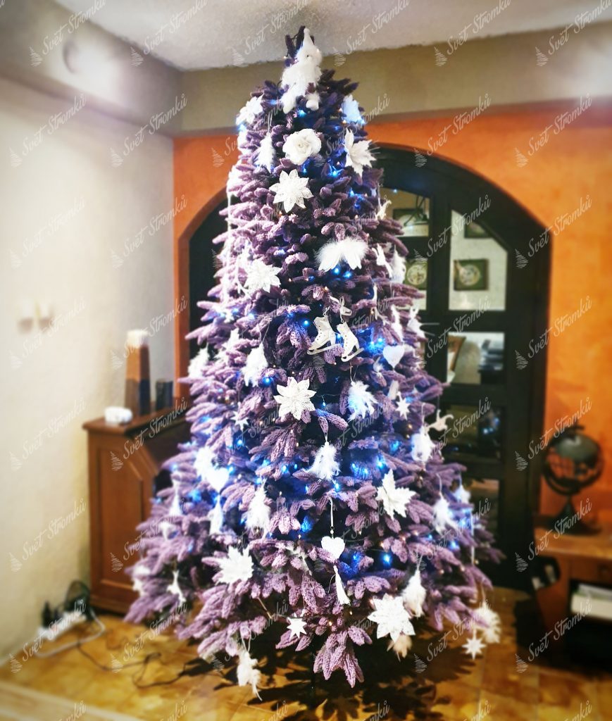 Fialový vánoční stromek ozdobený bílými květy a vánočními ozdobami