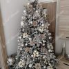Ozdobený umělý vánoční stromek 3D Smrk Královský 210cm stříbrnými pírky a koulemi doplněné bílými květy.