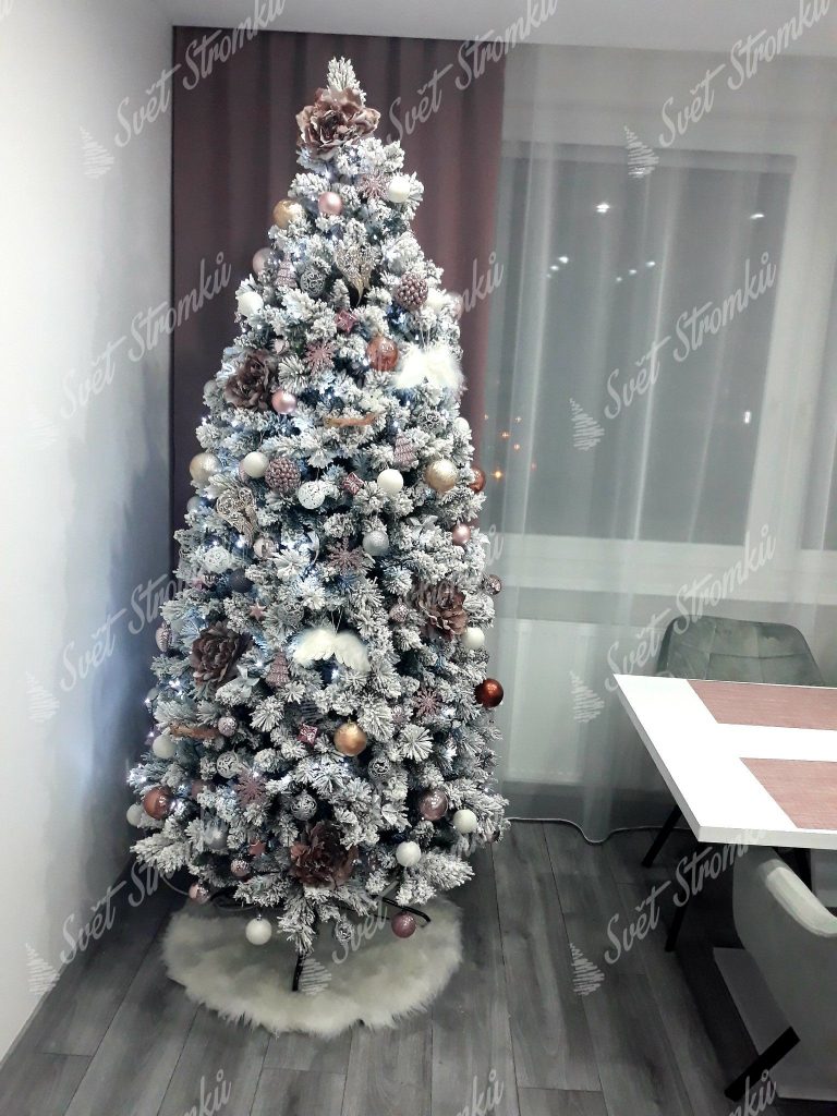 Husty bílý vánoční stromeček zdobený stříbrnými koulemi a bílými andělskými křídly.