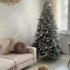 Zasněžený vánoční stromek ozdobený zlatými a pudrovými vánočními ozdobami.