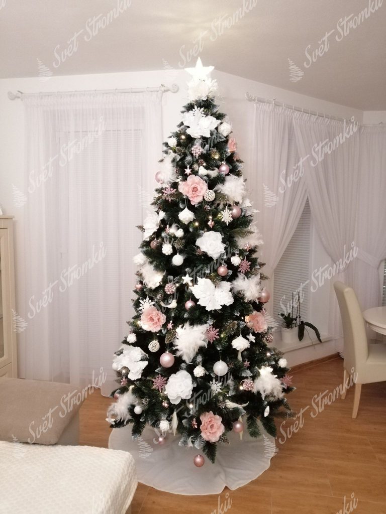 Zelený vánoční stromeček ozdobený bílými vánočními květy a bledě růžovými růžemi.