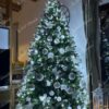 Umělý vánoční stromek FULL 3D Smrk Finský je ozdoben stříbrnými a bílými ozdobami.