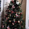 Umělý vánoční stromek FULL 3D Smrk Finský je ozdoben měděnými, červenými a bílými dekoracemi.
