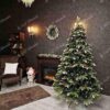 Umělý vánoční stromek 3D Jedle Zasněžená má zasněžené konce větviček a je ozdobena šiškami a červenými bobulemi.