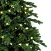 Detailní fotka větviček s 3D jehličím. Kolem větviček jsou omotané LED vánoční světýlka svítící v teplé bílé barvě.