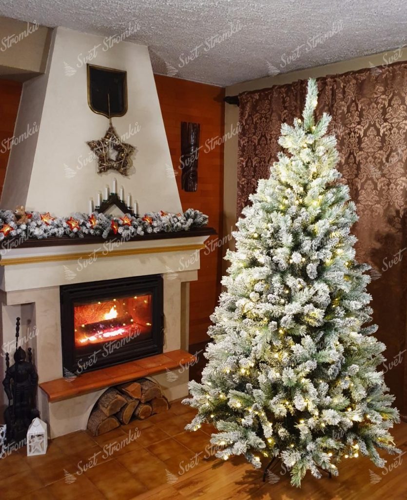 Bílý, celo zasněžený stromek s LED osvětlením v obýváku na Vánoce.