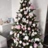 Umělý vánoční stromek 3D Smrk Skandinávský 180cm je vkusně vyzdoben bílými a růžovými dekoracemi.