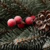 Detail vánočního věnečku pokrytého bílými chomáčky, borovými šiškami a červenými lesními plody.