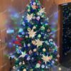 Umělý vánoční stromek 3D Smrk Alpský XL 210cm je hustě zdobený různými ozdobami.