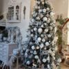 Umělý vánoční stromek 3D Smrk Ledový Úzký 210cm je moderně zdobený bílými a stříbrnými ozdobami.