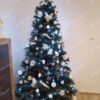 Umělý vánoční stromeček s tmavozelenými větvičkami, ozdobený bílo-zlatými ozdobami a bílým osvětlením, v obýváku