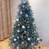 Umělý vánoční stromeček s ledově stříbrnými větvičkami, ozdobený bílo - zelenými ozdobami, v obýváku