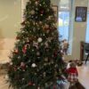 Mohutný, široký a vysoký zelený umělý vánoční stromeček, ozdobený červeno-zlatými ozdobami, ve velkém obývacím pokoji