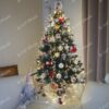 Malý umělý vánoční stromeček s tmavozelenými větvičkami, s postříbřenými konci větviček a dekorací krystalů ledu, ozdobený červeno-bílými ozdobami a teplým bílým osvětlením, v rohu obývacího pokoje