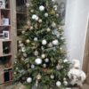 Světle zelený umělý vánoční stromek, ozdobený bílo-zlatými ozdobami, v obýváku