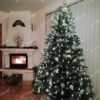 Zelený umělý vánoční stromeček, jemně ozdobený zlato-stříbrnými ozdobami, v obýváku