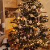Umělý vánoční stromeček se zelenými větvičkami, ozdobený bílými ozdobami a teplým bílým osvětlením, v obýváku