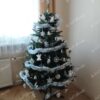 Umělý vánoční stromeček se zelenými větvičkami, ozdobený bílými ozdobami, v obýváku