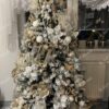 Zasněžený umělý vánoční stromeček, hustě ozdobený bílo-zlatými ozdobami, v obýváku