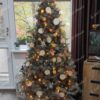 Stříbrný umělý vánoční stromek, ozdobený přírodními ozdobami, v obýváku