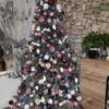 Umělý vánoční stromeček se stříbrnými větvičkami, ozdobený růžovo-bordovými ozdobami, v obýváku