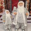 Vánoční dekorace Mikuláš Ledový, na sobě má stříbrný kabát s bílou kožešinou a v ruce drží dárky.