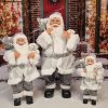 Dekorace Santa Claus Stříbrný, má na sobě stříbrný kabát a v ruce plyšovou hračku.