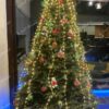 Umělý vánoční stromeček FULL 3D Jedle Normandská je elegantně zdoben červenými a zelenými dekoracemi.
