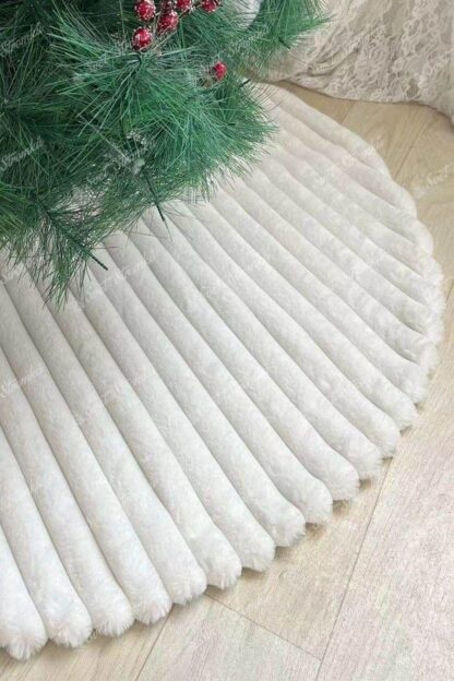 Bílý pruhovaný koberec pod stromeček má bílou kožešinu a pruhovaný vzor